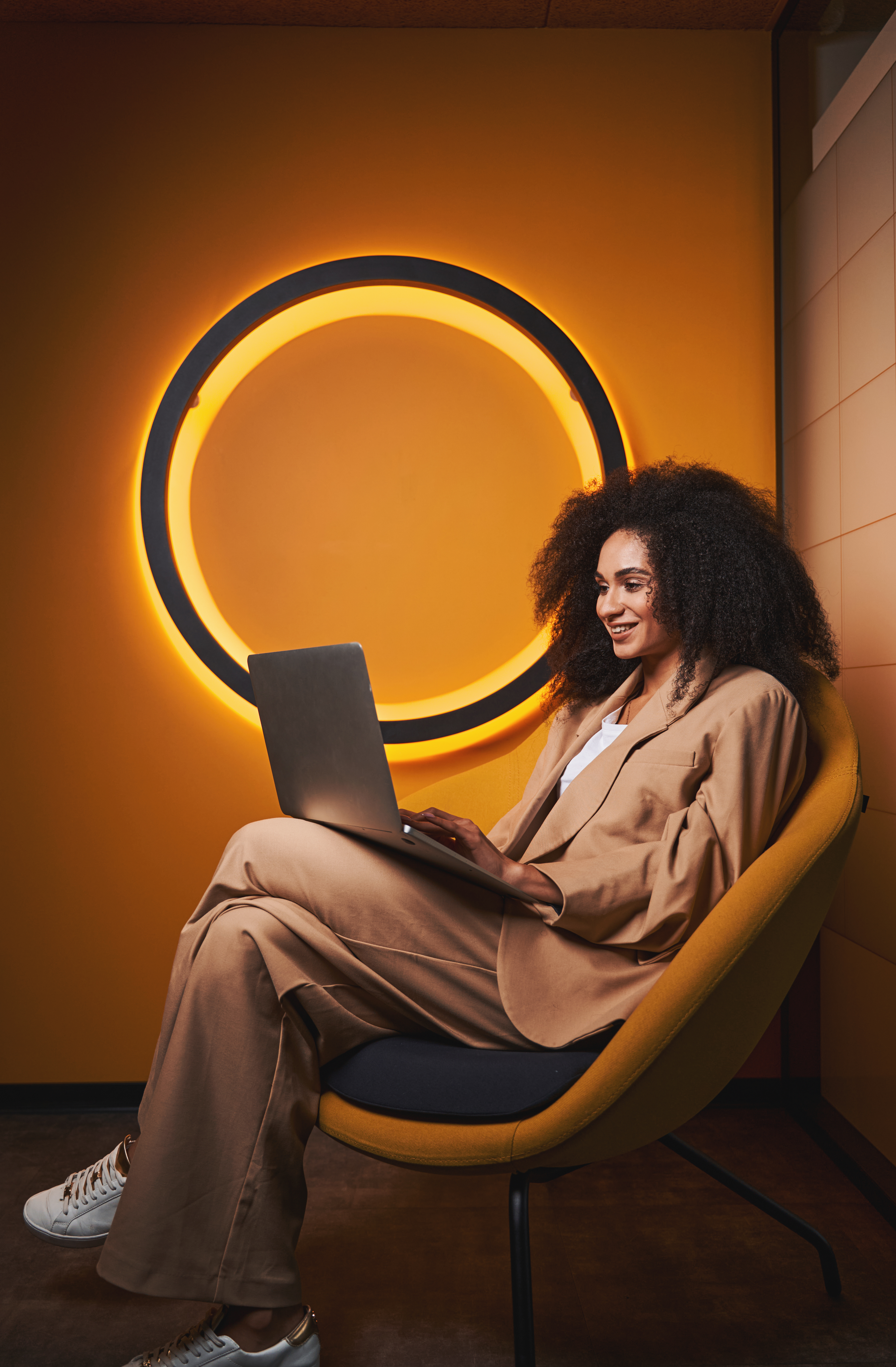 Woman sat looking at laptop with an illuminated circle on the wall in the background