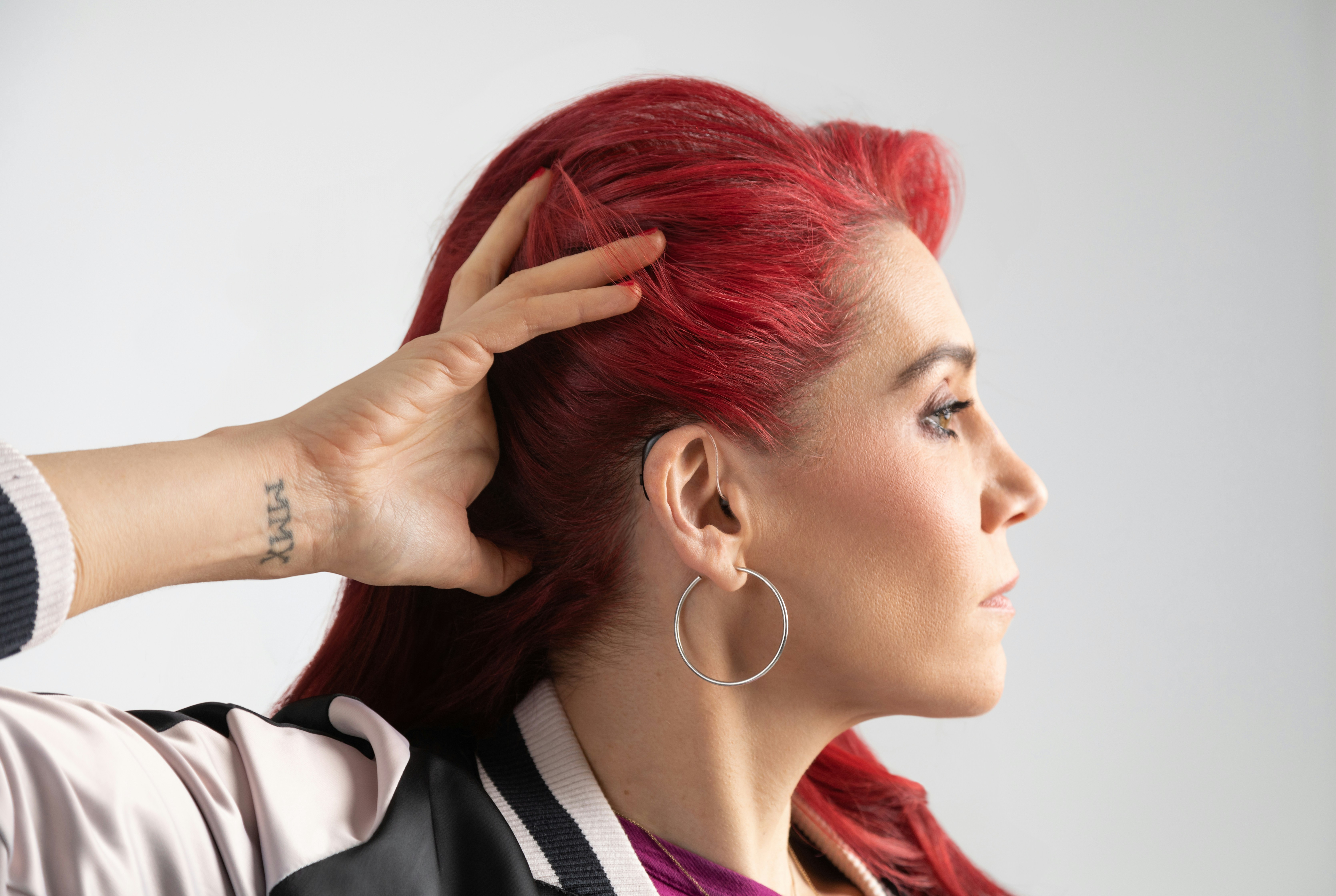 Woman raising her hair to show she's wearing a hearing aid