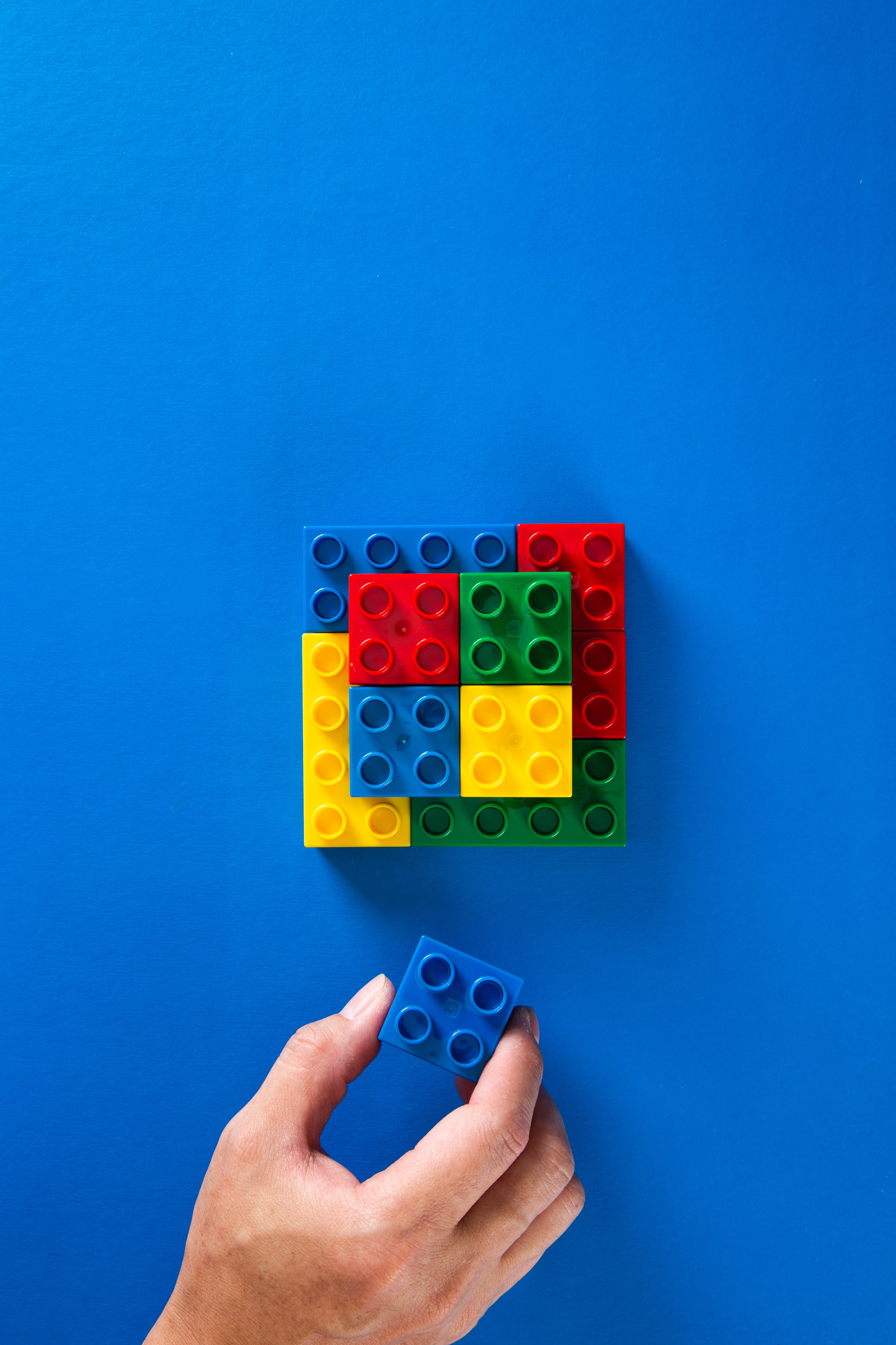 hand building lego blocks on a blue background